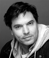 A black and white photo of a man looking at the camera.