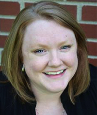 woman with short blonde hair in front of brick wall