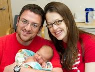 man and woman smiling with baby