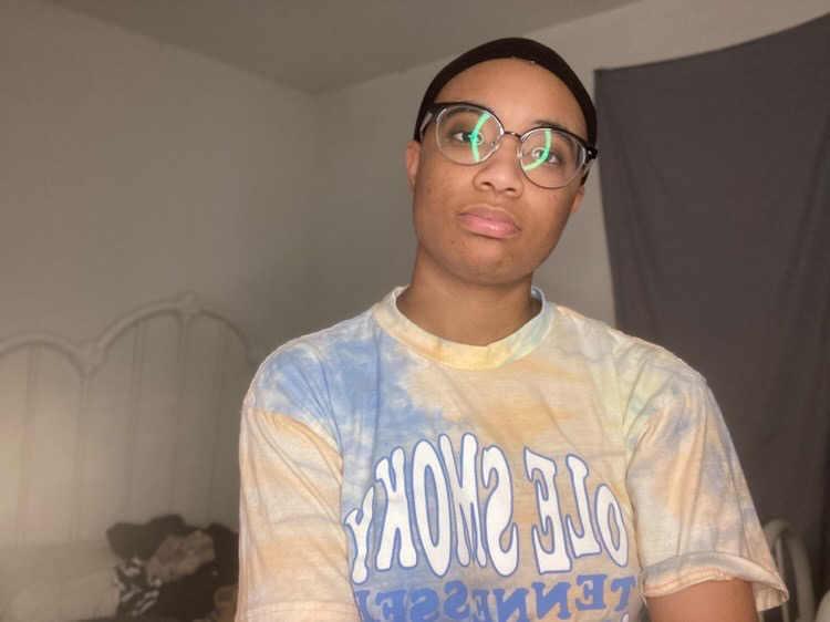 A young Black person wearing glasses and a tee shirt