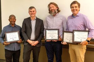 A group photo featuring Jonathan Choti, Dean Thomas Stubblefield, Tim Conrad, and Casey McArdle standing together and smiling, with Choti, Conrad, and McArdle holding their respective faculty award plaques.