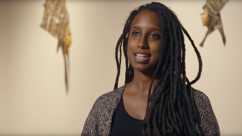 woman in art exhibit speaking to interviewer