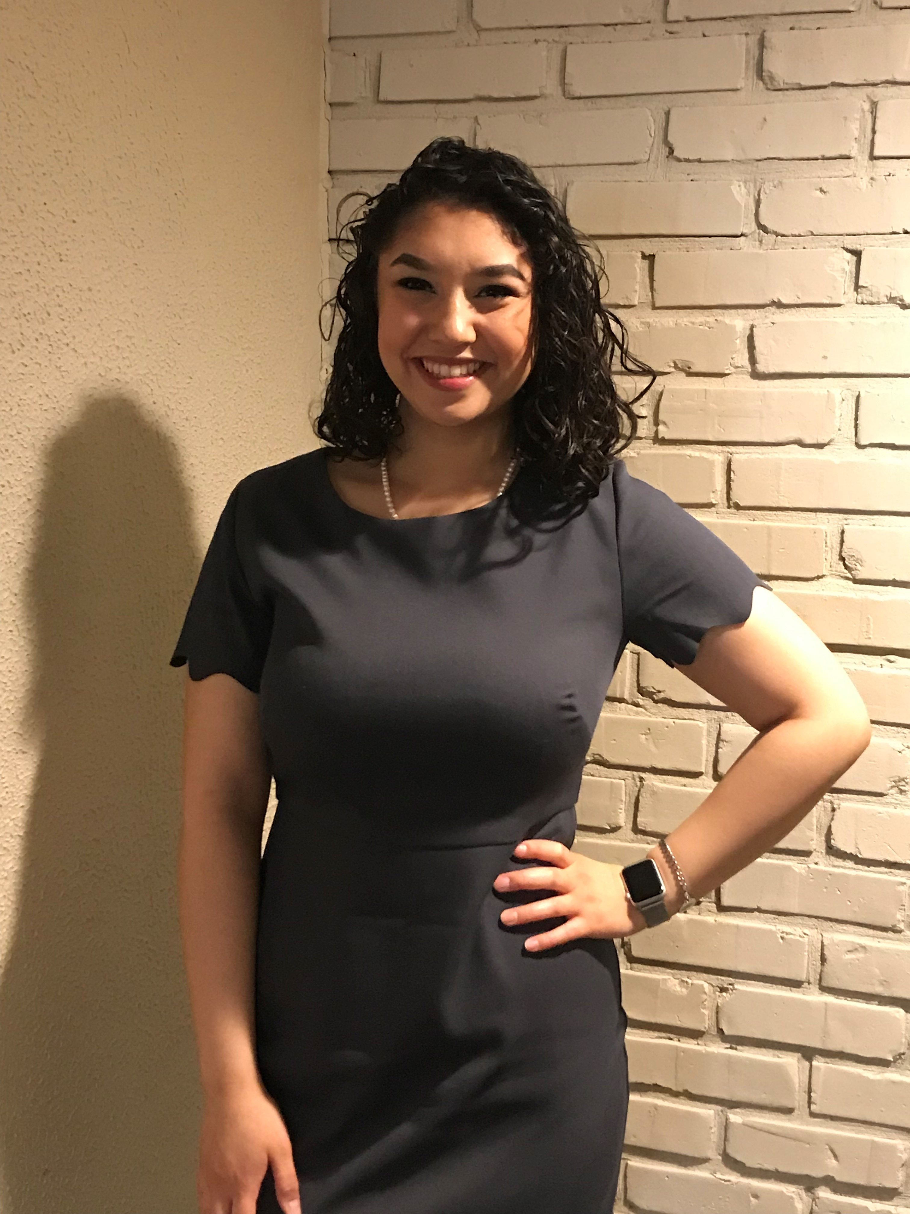 woman in black dress in front of brick wall