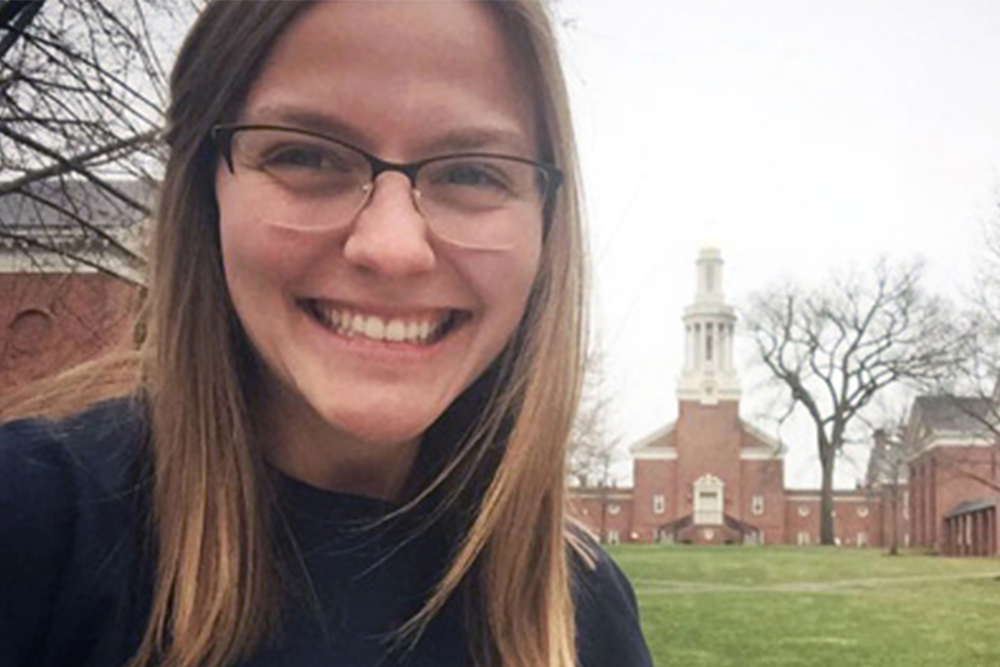 Woman with brown hair and glasses on a college campus