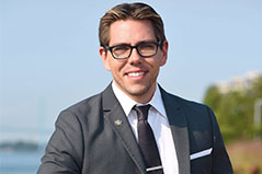 a man with short brown hair wearing glasses and a grey suit