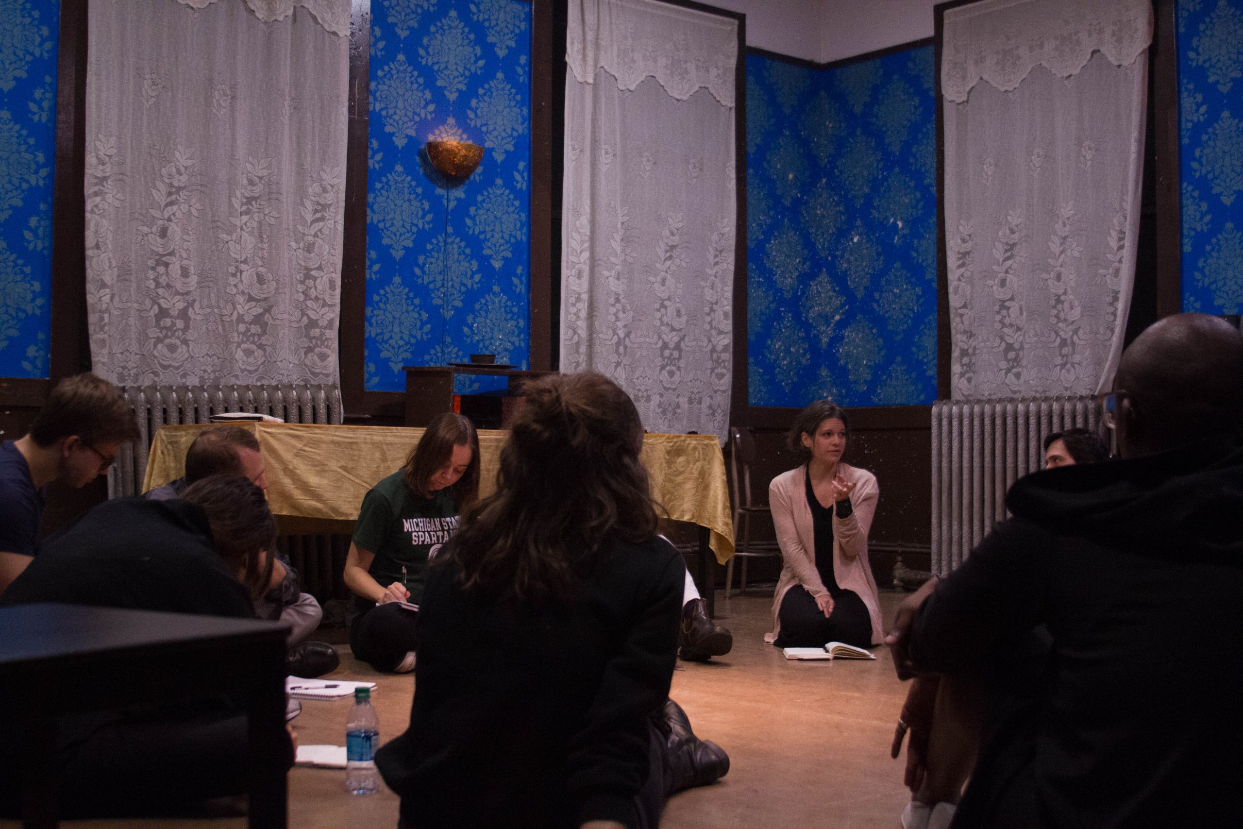 group of people sitting in a circle in a room with notebooks in front of them