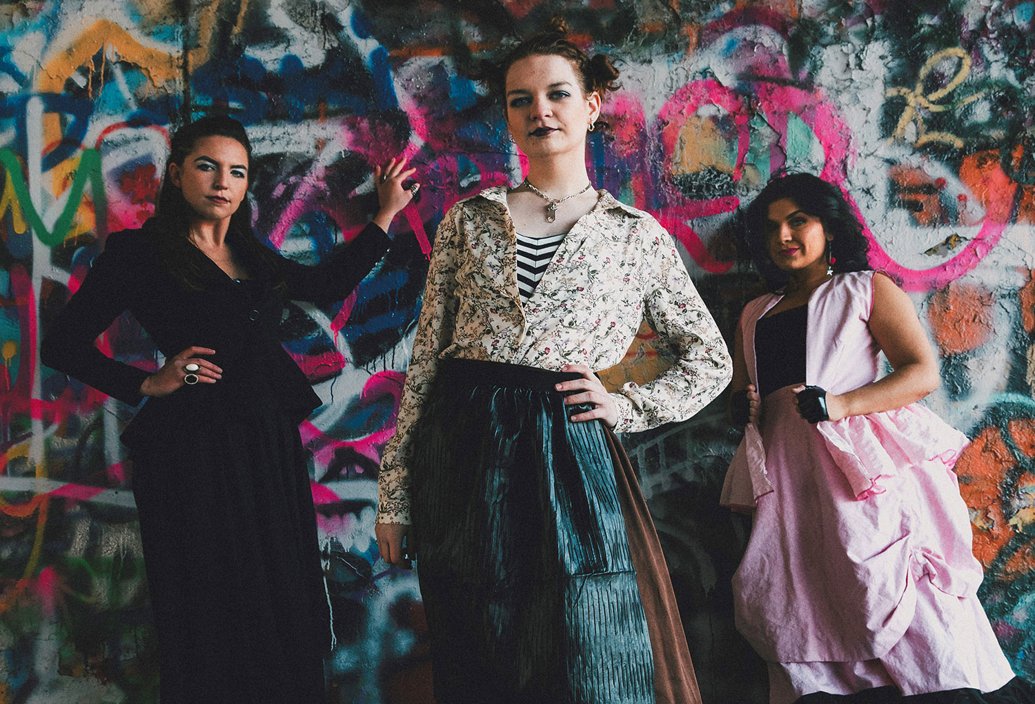 3 women leaning against a colorful wall