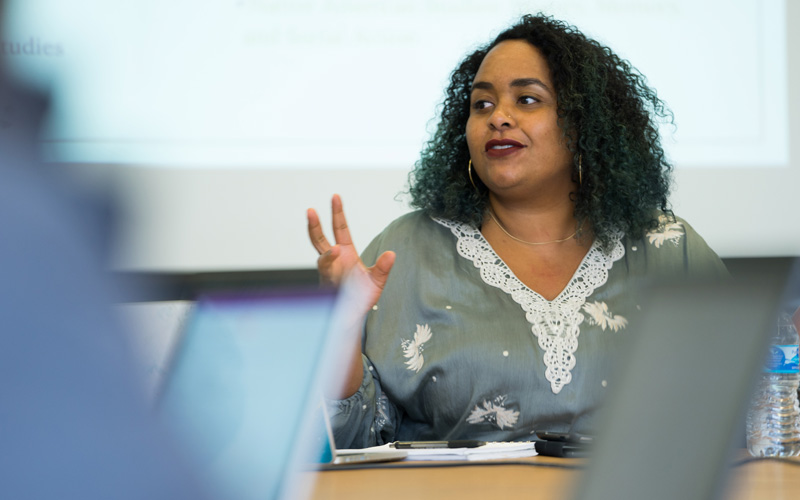 a woman in a grey shirt giving a speech/lecture