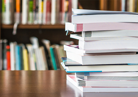 Books on a table with bookshelf in background