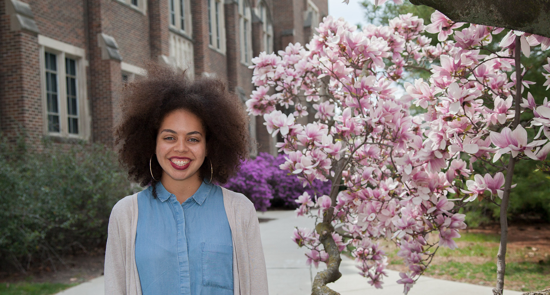 woman posing for a picture outside with spring flowers