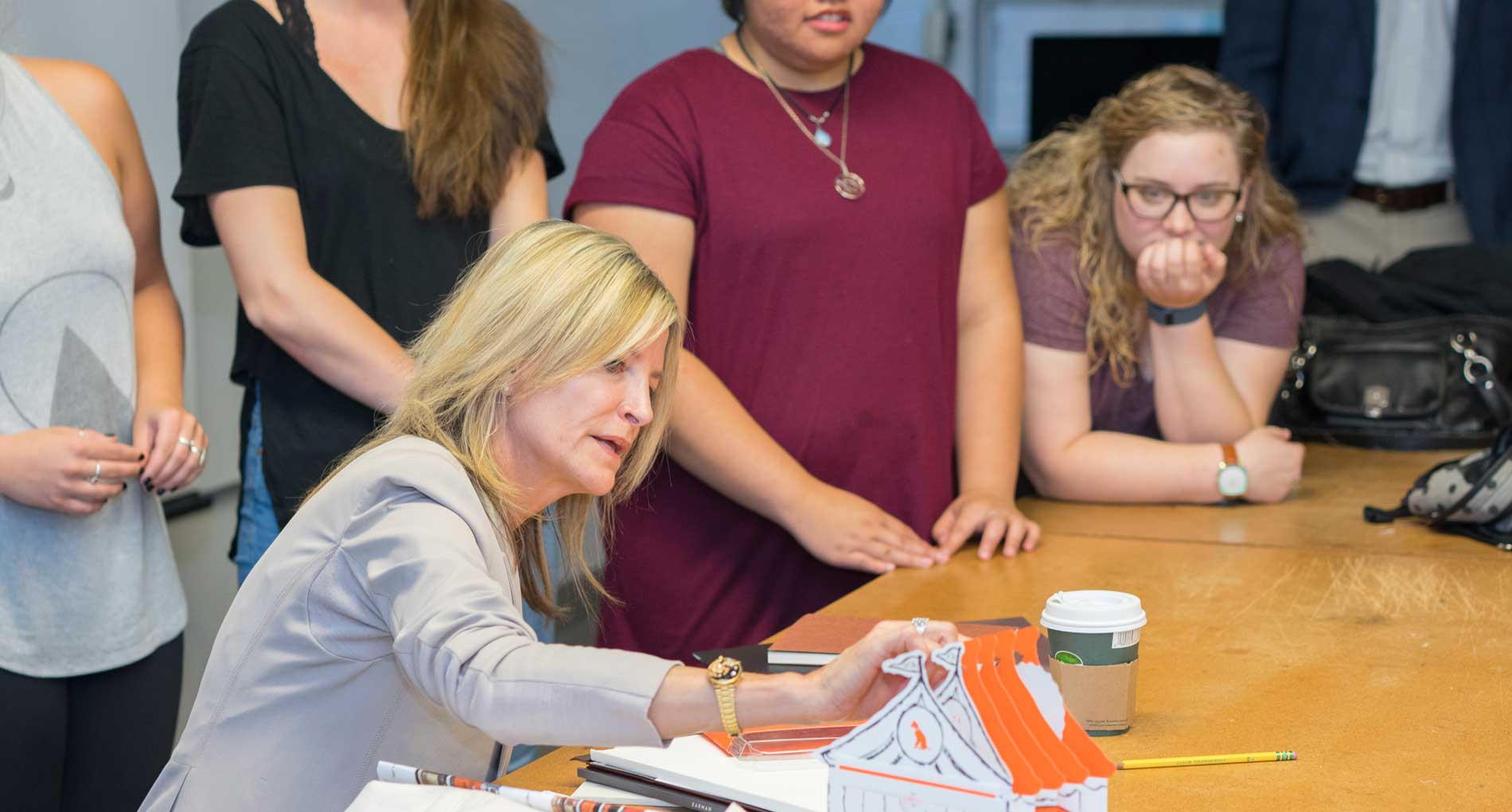 blonde woman working with students in classroom at msu
