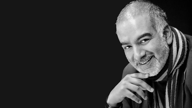 portrait of a man with a beard smiling, he is wearing a striped scarf with a suit
