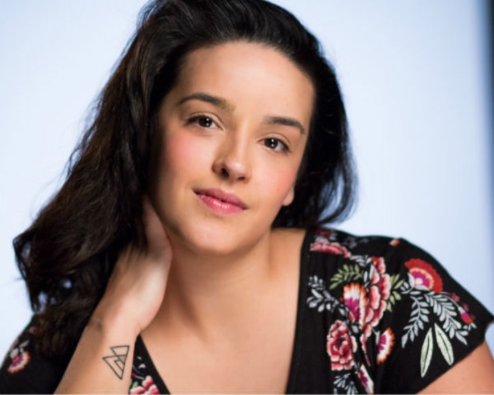 Woman with dark hair and a black shirt smiling at the camera