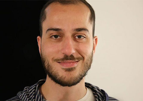 a man with short hair and facial hair wearing a stripped sweater