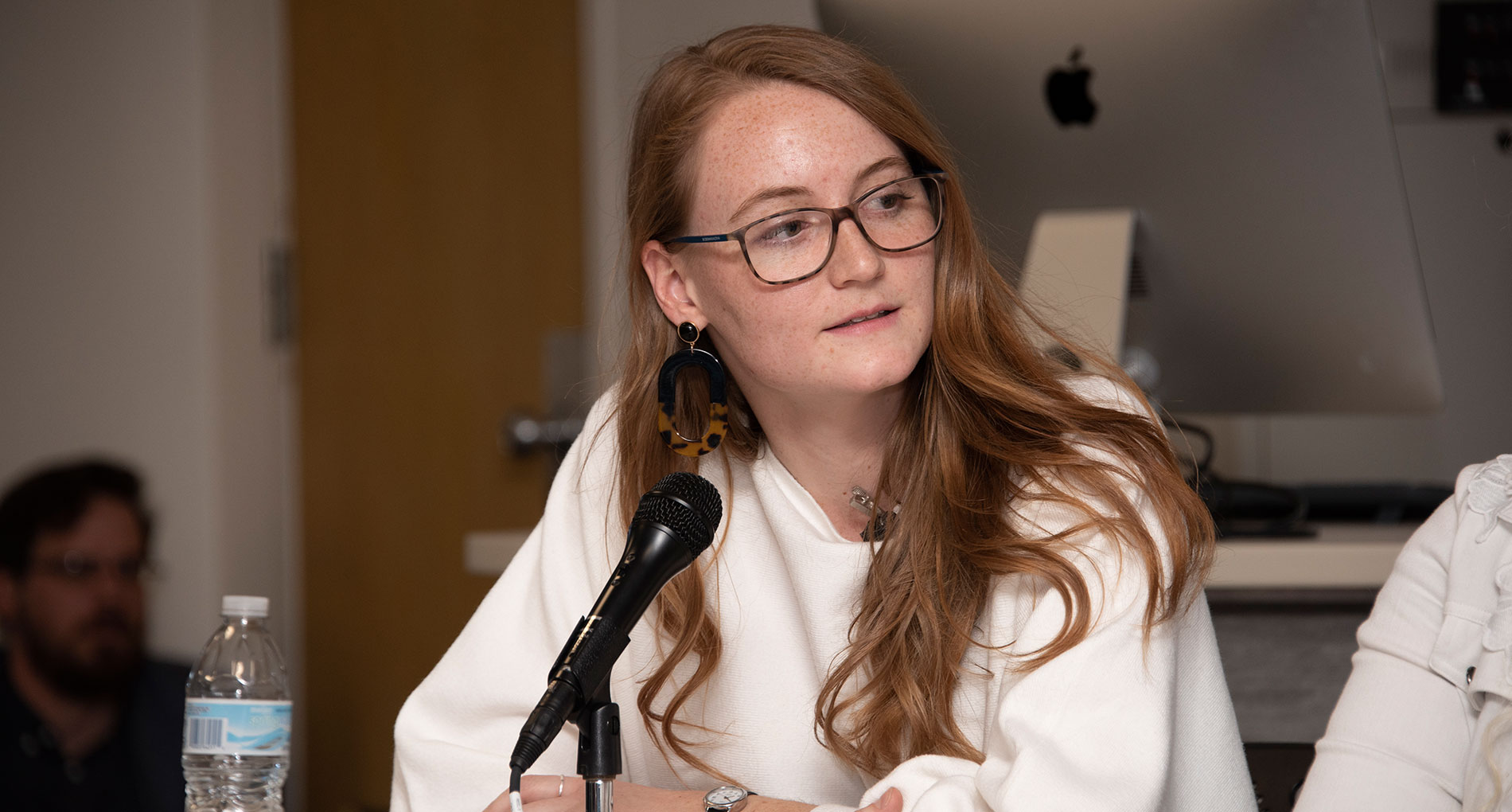Woman wearing a white shirt speaking into a microphone