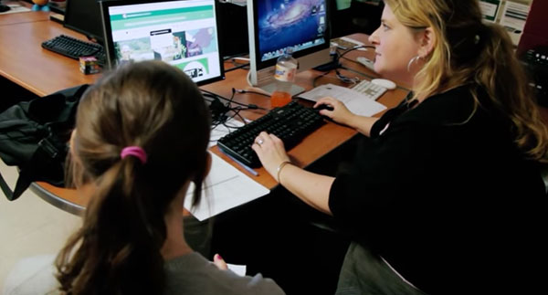 a professor using a computer while a student watches