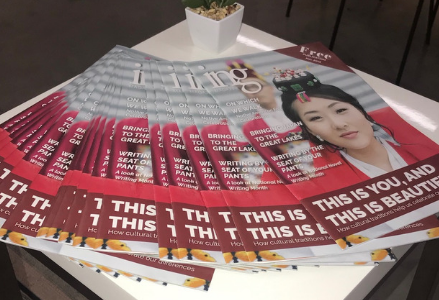 photo of a pile of all of the same magazines that have a photo of a woman who is wearing a read dress on a white table