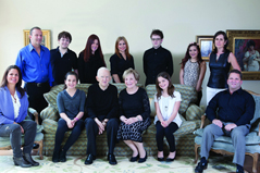 group a family of thirteen people sitting on a couch and standing around smiling for the camera