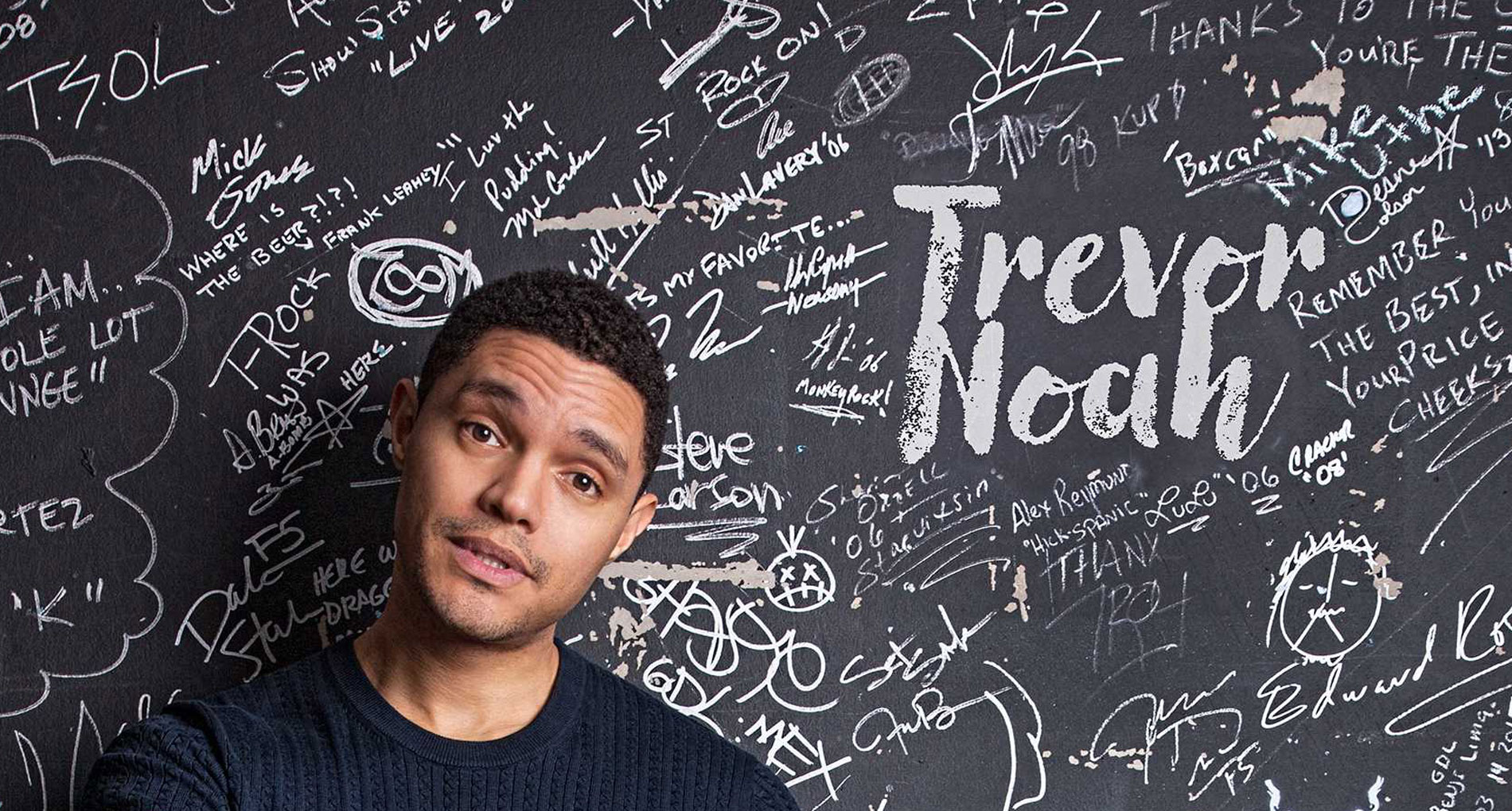 headshot of man standing against wall with writing