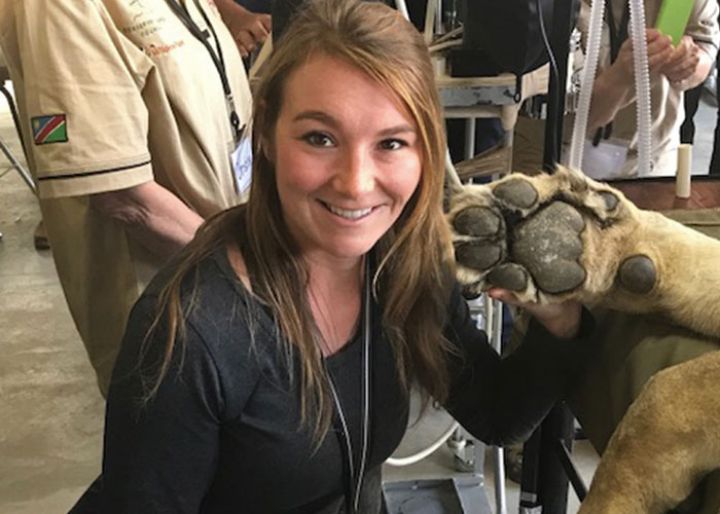 a girl with long brown hair holding a lion paw next to her face