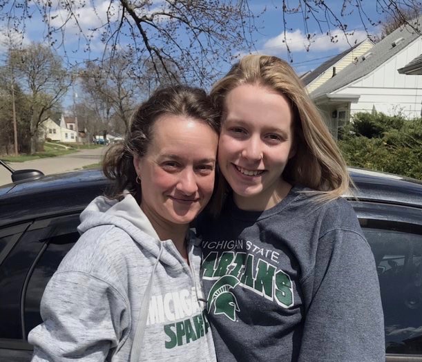 Two people taking a photo together wearing msu sweatshirts