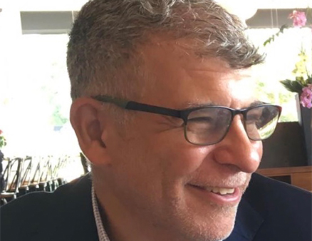 Headshot of a man with short gray hair and black frame glasses.