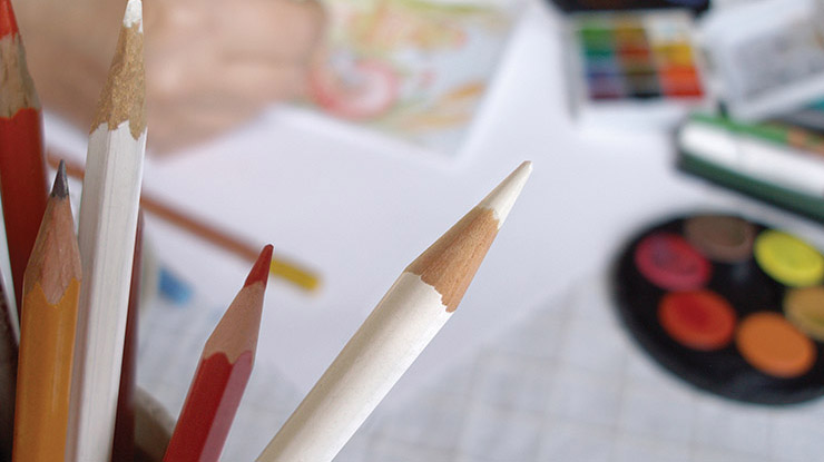closeup of colored pencils with an art desk in the background