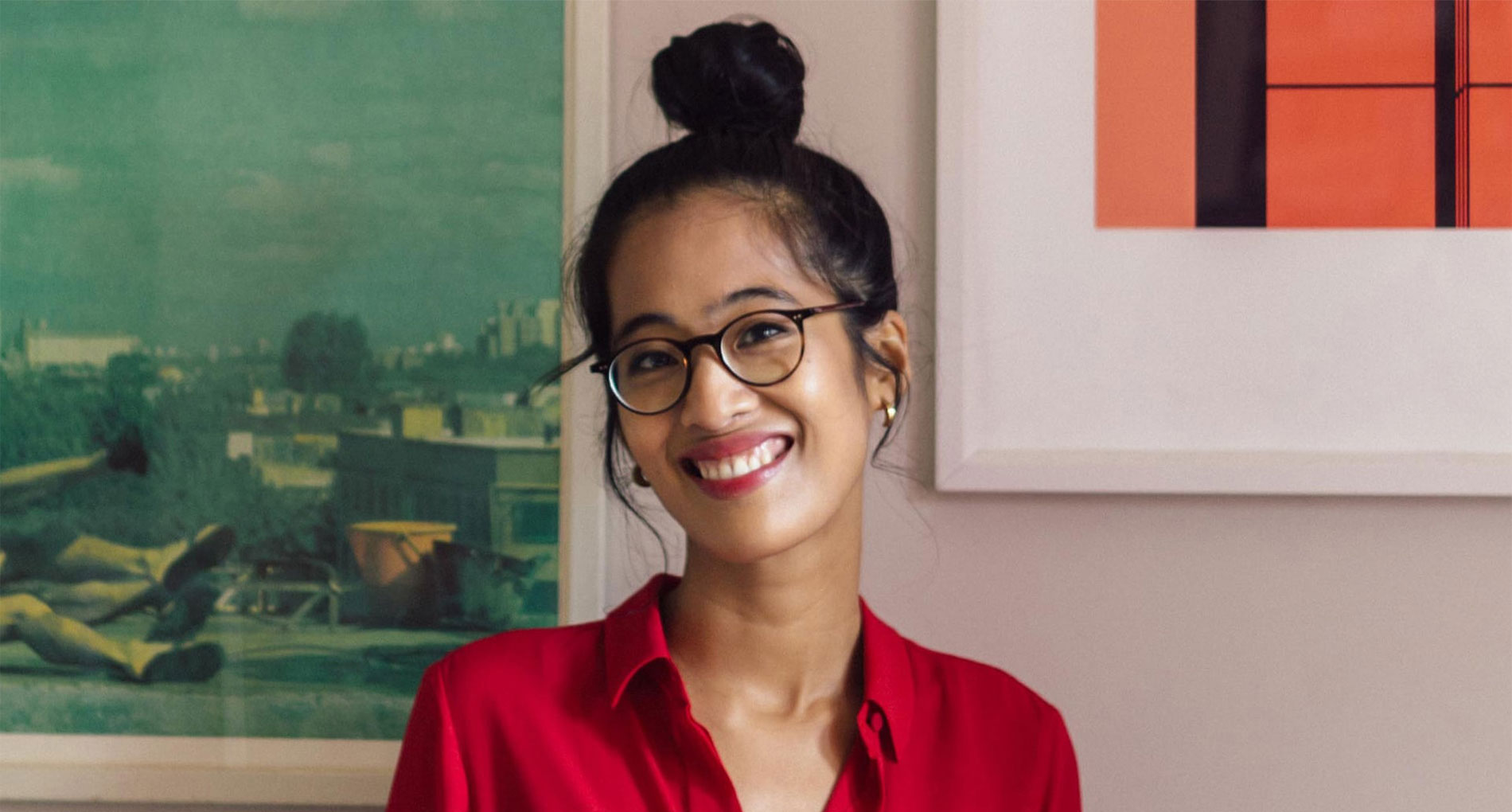 Woman with glasses in a red shirt smiling at the camera
