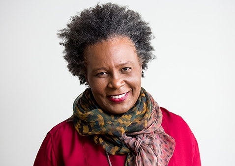 a woman with short dark hair wearing a colorful scarf and a red shirt