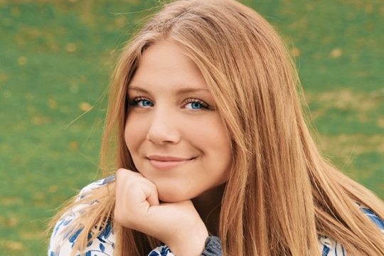 Woman with blonde hair sitting in a field of grass