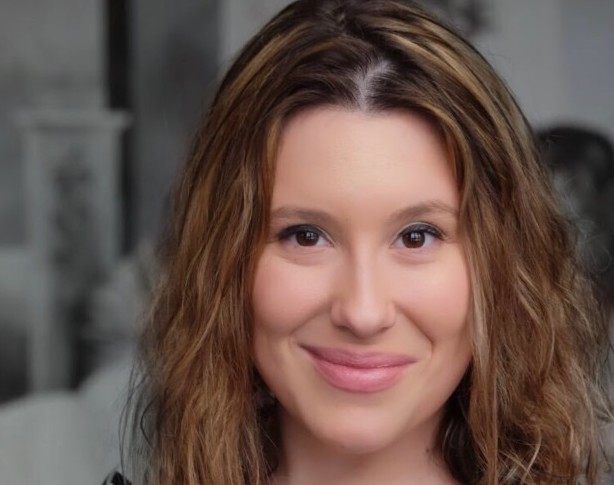 a girl with short brown hair wearing a grey and black shirt
