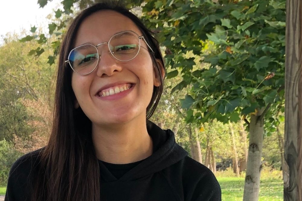 A picture of a woman with glasses and long hair smiling at the camera.