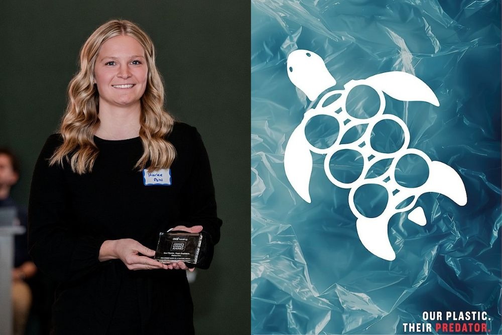 A woman stands indoors holding an ADDY Award plaque and smiling at the camera. Next to her is a graphic design poster showing a white sea turtle silhouette over a blue plastic-textured background, with circular cutouts resembling plastic six-pack rings. Text at the bottom reads, “Our plastic. Their predator.”
