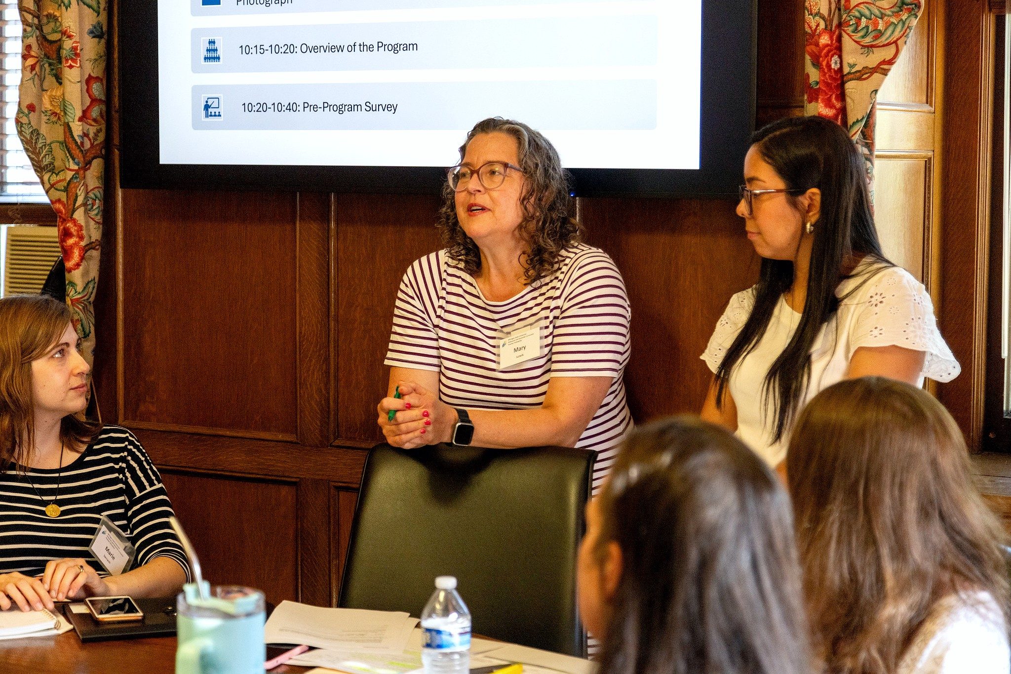 Mary Juzwik speaks to participants gathered around a conference table during a workshop session.