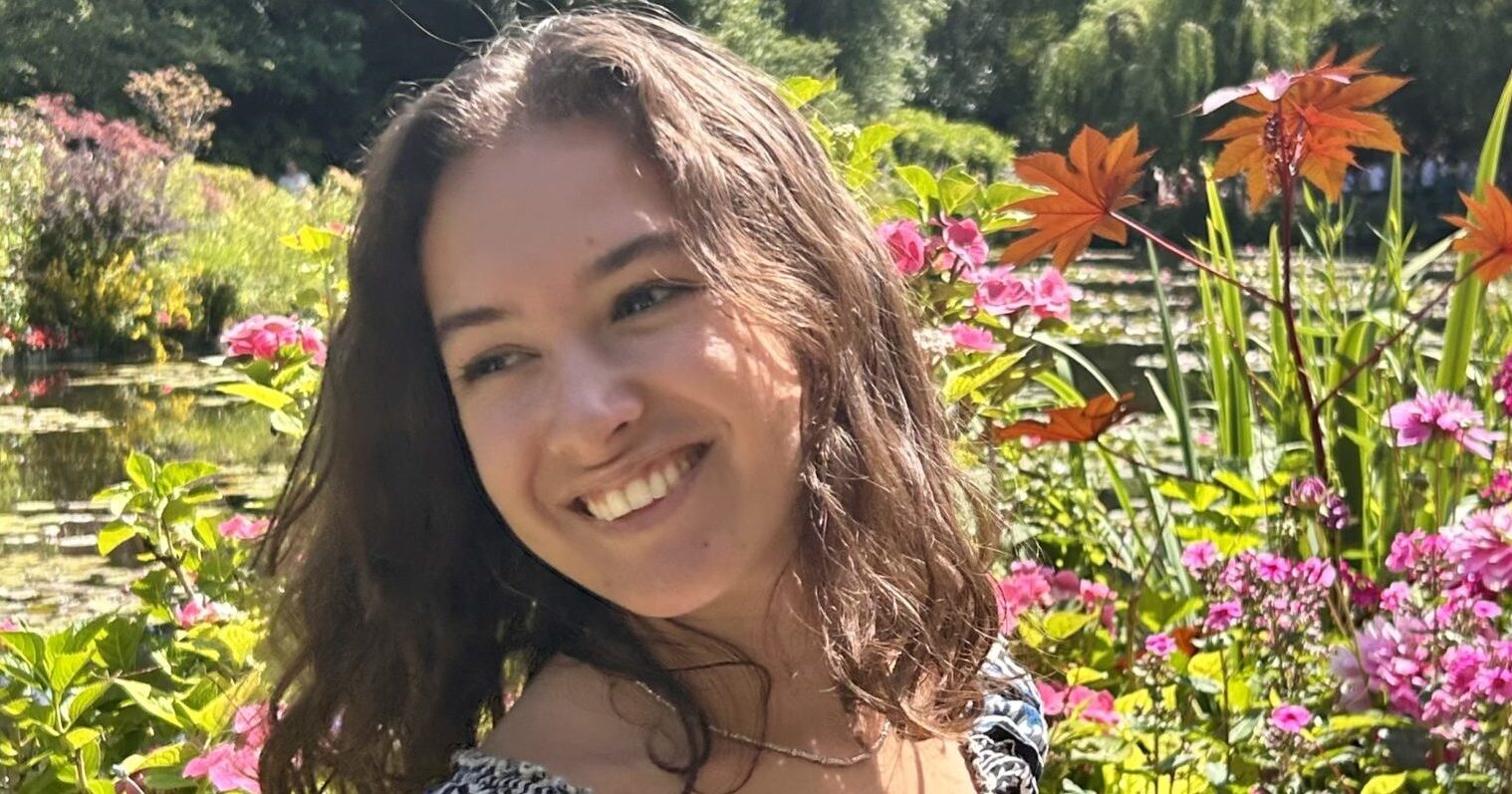 Margaux, standing in a garden, smiling